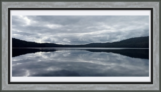 Framed photograph of a lake with mountains and cloudy sky
